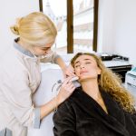 Professional young female doctor cosmetologist doing hydrafacial procedure in cosmetology clinic